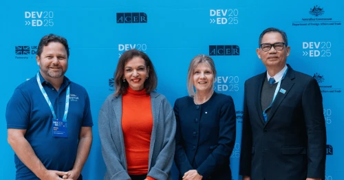 Image of a girl and a woman sitting in a field reading a book